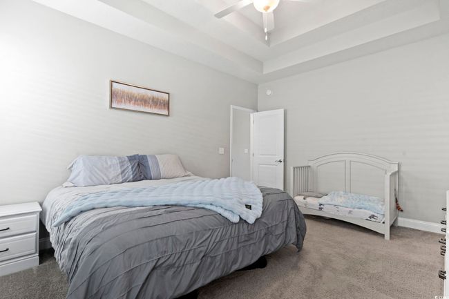 Carpeted bedroom featuring a ceiling fan, a tray ceiling, and baseboards | Image 26