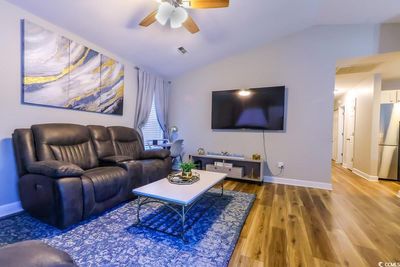 Living room with wood-type flooring, lofted ceiling, and ceiling fan | Image 3