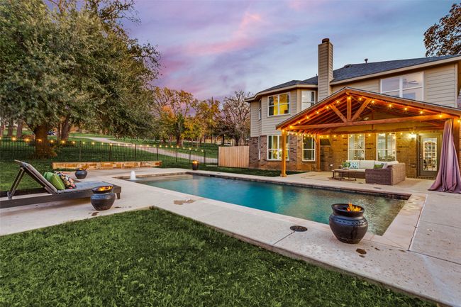 Pool at dusk with an outdoor hangout area, a gazebo, a fenced backyard, and a patio area | Image 4