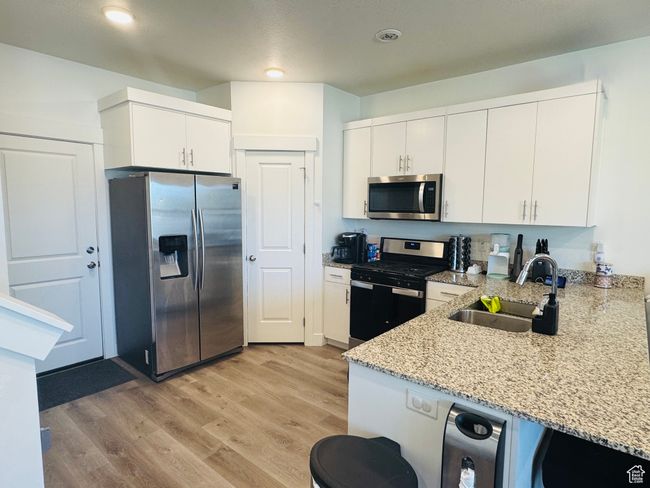 Kitchen with appliances with stainless steel finishes, light granite countertops, white cabinets, and recessed lighting | Image 4