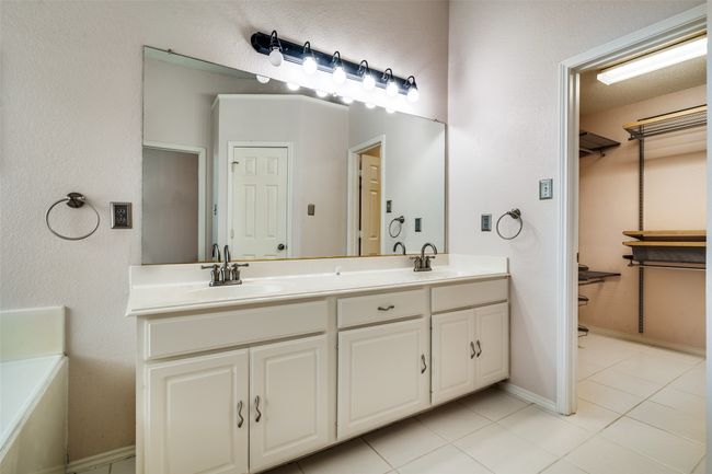 Bathroom with a walk in closet, light tile patterned floors, and double vanity | Image 22