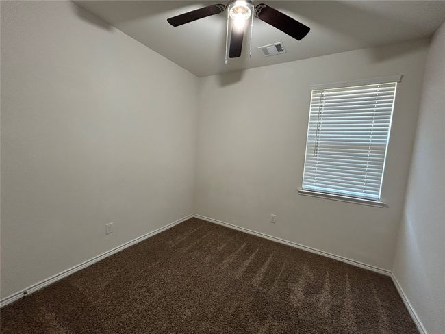 Empty room with dark carpet, ceiling fan, and baseboards | Image 11