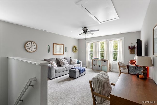 Living area with light colored carpet, attic access, ceiling fan, and visible vents | Image 21