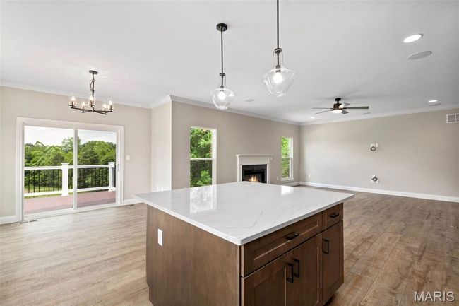Kitchen featuring open floor plan, a warm lit fireplace, light wood-type flooring, baseboards, and recessed lighting | Image 15