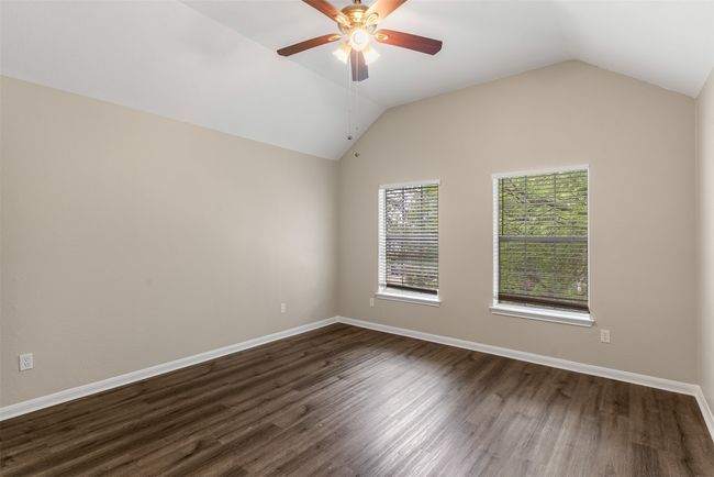 Empty room featuring dark wood-style flooring, baseboards, vaulted ceiling, and ceiling fan | Image 32