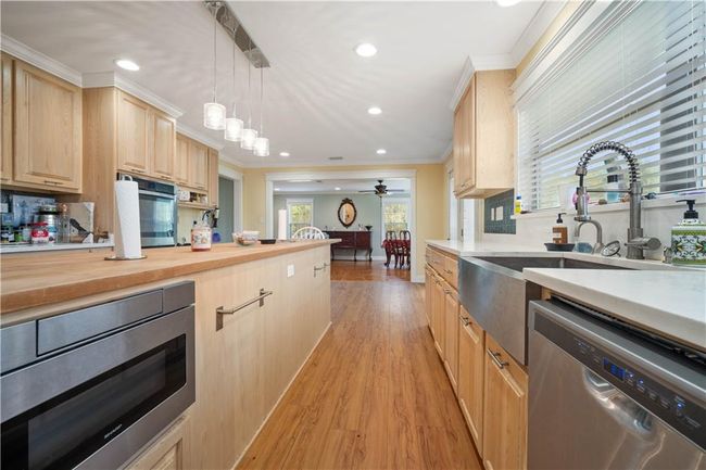 Kitchen featuring light wood finished floors, light brown cabinetry, stainless steel appliances, ceiling fan, and ornamental molding | Image 9