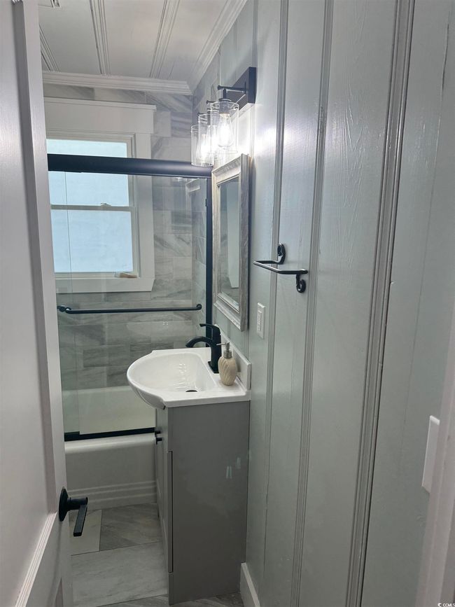 Bathroom featuring crown molding, vanity, and shower / bath combination with glass door | Image 25