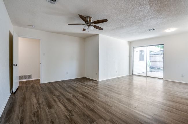 Empty room featuring a textured ceiling, ceiling fan, and dark wood finished floors | Image 11
