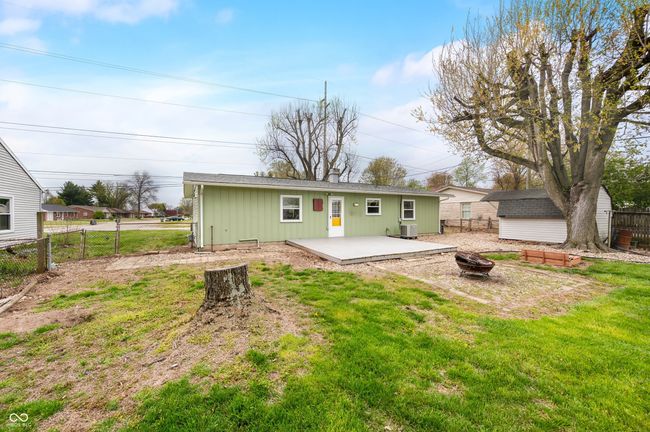 back of property featuring fence, a yard, a patio area, an outbuilding, and a fire pit | Image 7