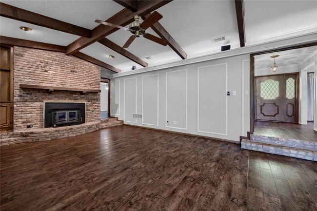 Unfurnished living room with visible vents, ceiling fan, vaulted ceiling with beams, and dark wood-style floors | Image 9