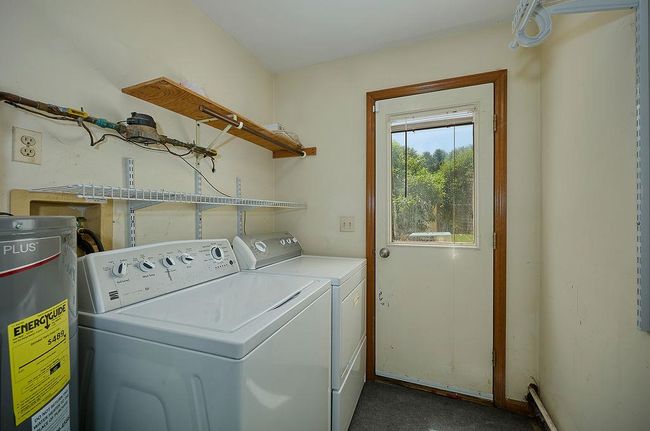 Laundry room first floor off kitchen featuring water heater and washing machine and clothes dryer | Image 24