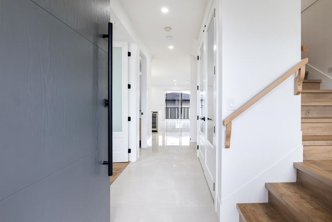 Corridor with stairs, finished concrete floors, recessed lighting, and wine cooler | Image 6