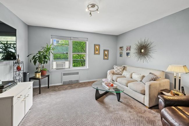 Living area featuring radiator heating unit, baseboards, carpet floors, and cooling unit | Image 15