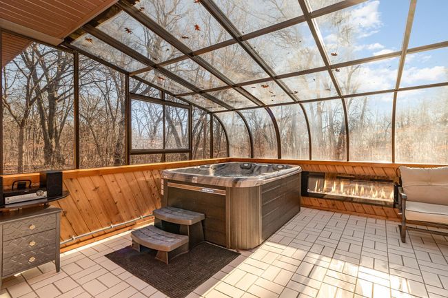 Envision year-round relaxation in the new hot tub within the glass solarium, accompanied by the ambiance of an electric fireplace. The sunroom feels like a spa retreat with the private & tranquil views of nature. | Image 10