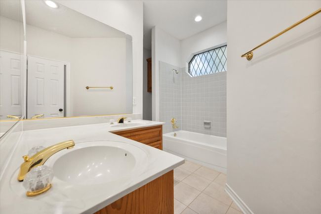 Ensuite bath between the secondary bedrooms has dual sinks, ceramic tile floor, a tub shower enclosure, custom oval window and semi-private potty area. | Image 35