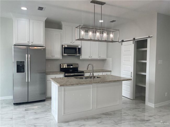 Kitchen with stainless steel appliances, a sink, light marble finish flooring, baseboards, and recessed lighting | Image 5