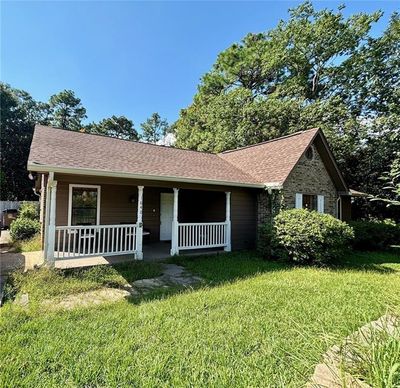 Single story home with a front lawn and covered porch | Image 1