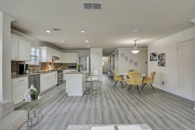 Kitchen featuring stainless steel appliances, light hardwood / wood-style floors, a kitchen bar, light stone counters, and a center island | Image 20