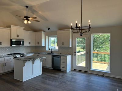 Kitchen featuring stainless steel appliances, a healthy amount of sunlight, lofted ceiling, and white cabinetry | Image 3