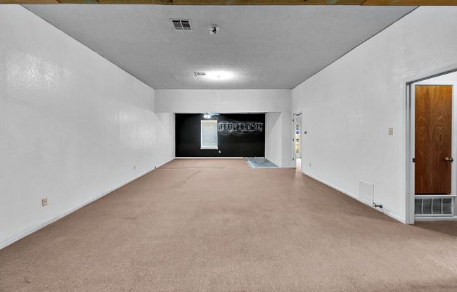 Carpeted empty room with baseboards, a textured ceiling, and fire sprinkler in ceiling | Image 10