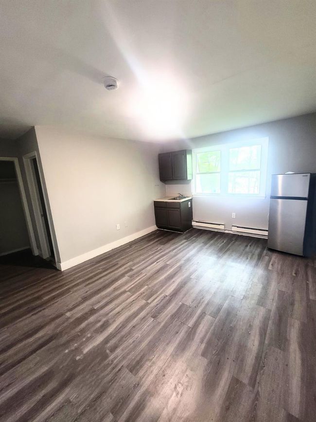 Unfurnished living room with dark wood-style floors, a baseboard heating unit, and baseboards | Image 22