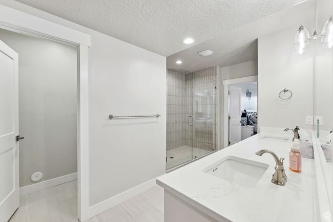 Bathroom featuring a textured ceiling, recessed lighting, a stall shower, and a sink | Image 26