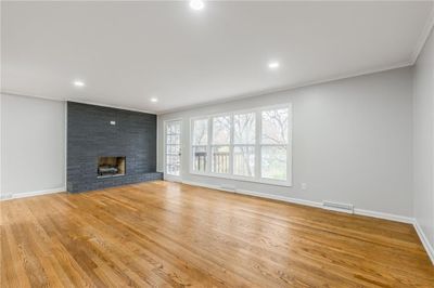 Unfurnished living room with a fireplace, light wood-type flooring, and crown molding | Image 3