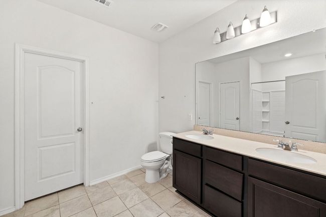 Bathroom with double vanity, tile patterned flooring, and a shower | Image 19