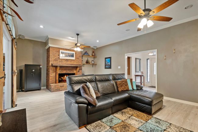 Living area featuring ceiling fan, light wood-type flooring, recessed lighting, a brick fireplace, and baseboards | Image 8