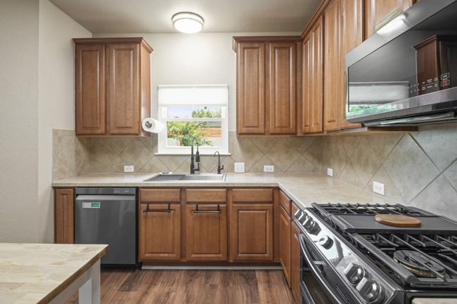 Kitchen featuring stainless steel appliances, a sink, light countertops, and dark wood finished floors | Image 13