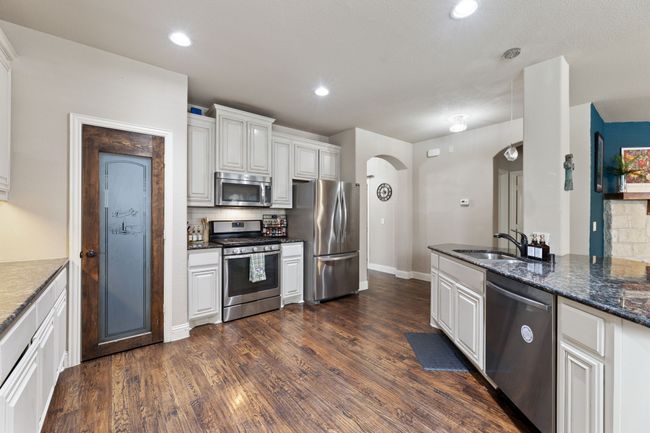 Kitchen featuring dark wood finished floors, tasteful backsplash, arched walkways, and stainless steel appliances | Image 6