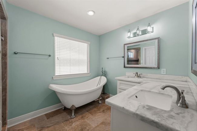 This bathroom features a classic freestanding clawfoot tub. It includes a window for natural light. | Image 23