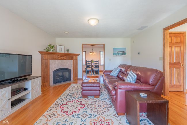 living room with a tiled fireplace, visible vents, and light wood-style flooring | Image 8