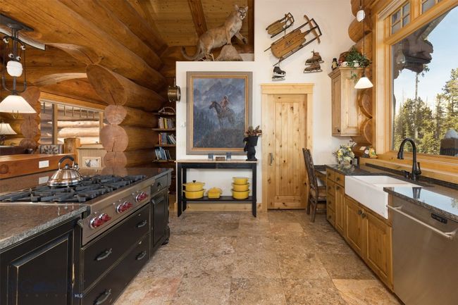 Main level kitchen with Wolf range & exhaust venting, cookbook storage and pantry entrance. | Image 33
