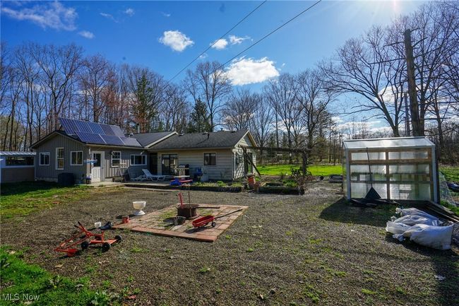 Back of house featuring an exterior structure, roof mounted solar panels, an outbuilding, and board and batten siding | Image 4