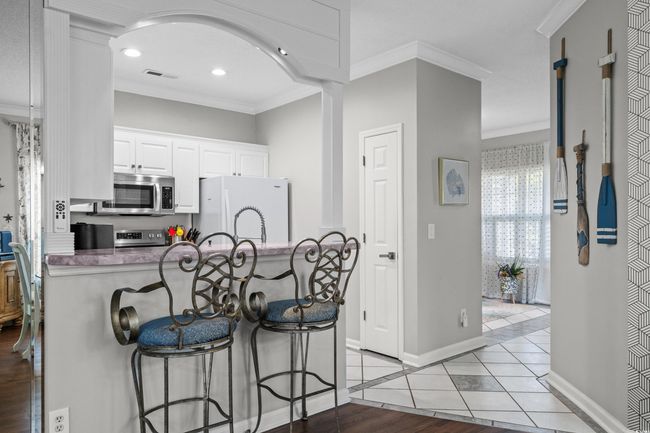 Kitchen featuring appliances with stainless steel finishes, crown molding, a breakfast bar area, baseboards, and white cabinets | Image 14