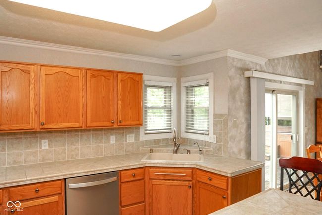 kitchen with dishwasher, decorative backsplash, tile counters, and an island | Image 10