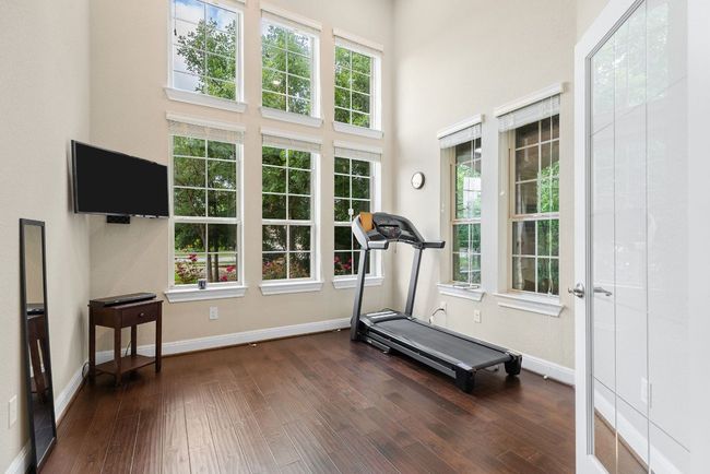 Workout area featuring dark wood-type flooring, baseboards, and a high ceiling | Image 18