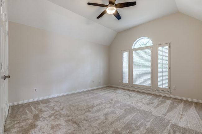 Carpeted empty room featuring vaulted ceiling, ceiling fan, and baseboards | Image 19