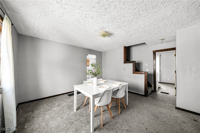 Dining space with a textured ceiling, visible vents, baseboards, stairway, and carpet floors | Image 7