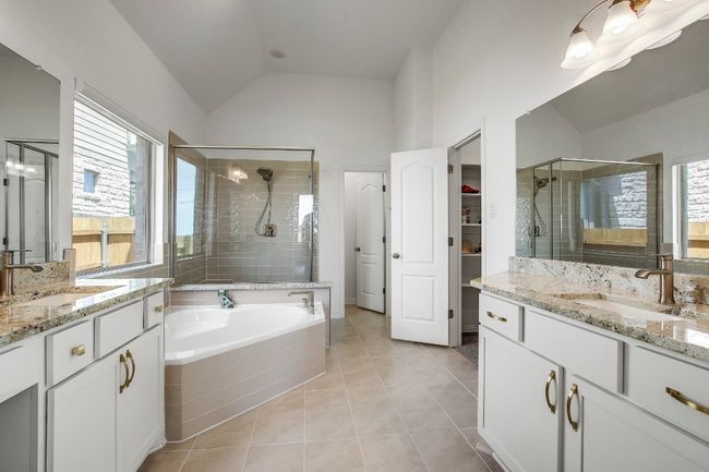 Full bathroom with a stall shower, two vanities, lofted ceiling, tile patterned flooring, and a garden tub | Image 20