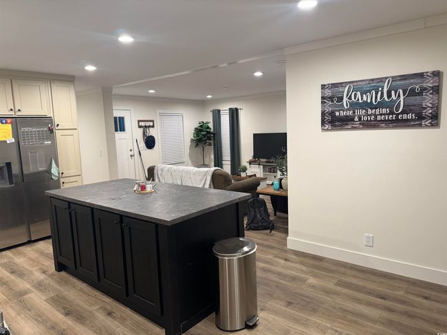 Kitchen featuring freestanding refrigerator, dark countertops, light wood-type flooring, crown molding, and a kitchen island | Image 5