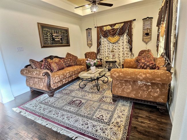 Living room with crown molding, wood finished floors, a ceiling fan, and baseboards | Image 10