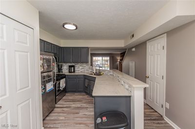 Kitchen featuring light hardwood / wood-style floors, gray cabinetry, sink, kitchen peninsula, and appliances with stainless steel finishes | Image 3