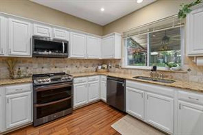 Kitchen with tasteful backsplash, light countertops, stainless steel appliances, white cabinetry, and a sink | Image 17