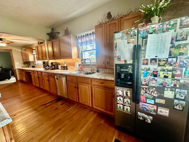 kitchen with appliances with stainless steel finishes, wood finished floors, light countertops, a ceiling fan, and brown cabinetry | Image 14