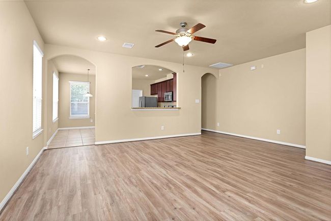 The entry opens to a spacious, open-concept floor plan featuring a large living room that blends comfort with style. Luxury vinyl flooring flows seamlessly throughout, enhancing the home’s cohesive, modern design. | Image 5