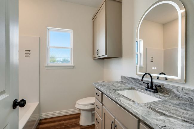 Full bath with toilet, baseboards, wood finished floors, vanity, and a tub | Image 22