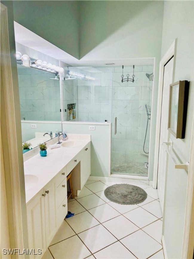Full bathroom featuring a marble finish shower, double vanity, and tile patterned floors | Image 5