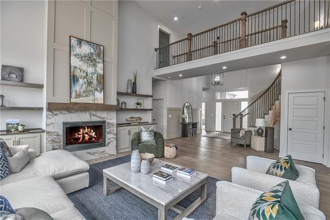 Living room with a premium fireplace, hardwood / wood-style flooring, and a towering ceiling | Image 6